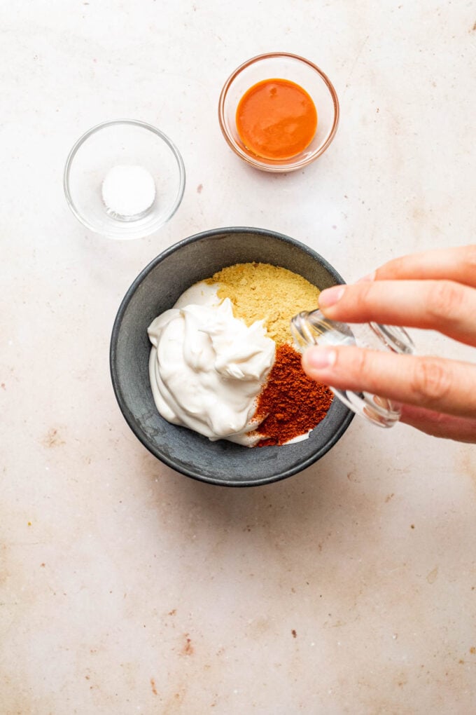 hand pouring paprika into mayo bowl