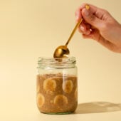 hand with gold spoon and banana oats in jar