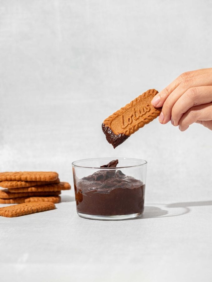 hand dipping cookie into chocolate dip