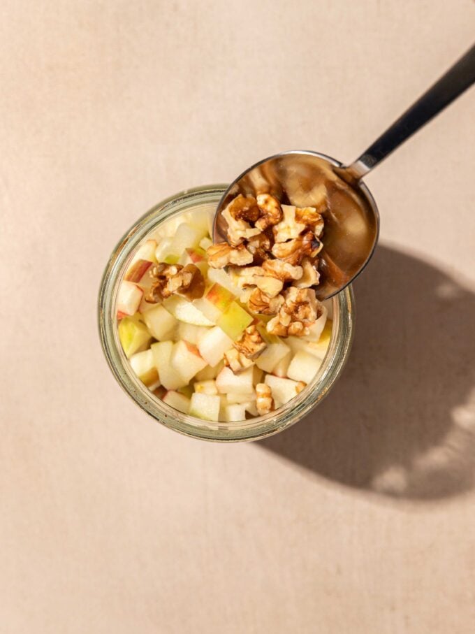 spoon with walnuts and apples in jar