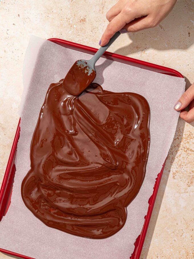 hand spreading chocolate on baking sheet